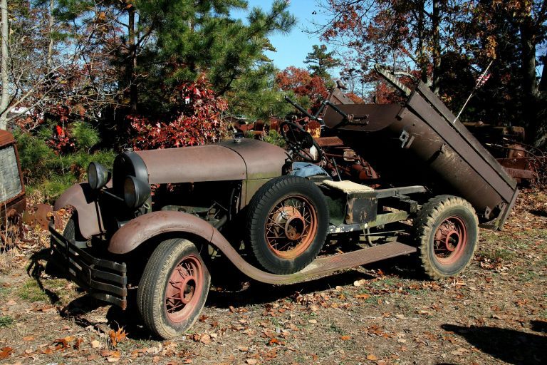 A classic vintage car rusting in a field