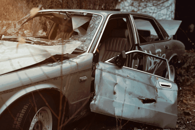 A fully wrecked car with broken windows and doors