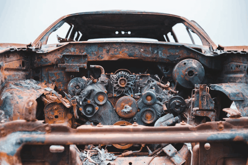 Close-up of a rusted car engine inside a burned-out vehicle.