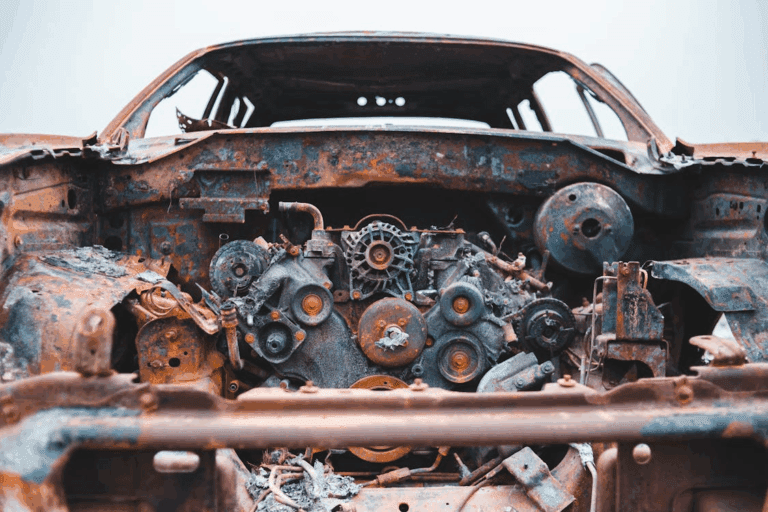 Close-up of a rusted car engine inside a burned-out vehicle.